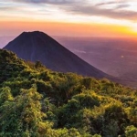 Misty Nicaraguan volcano rising over green hills during the rainy season, showcasing lush vegetation and dramatic cloud cover